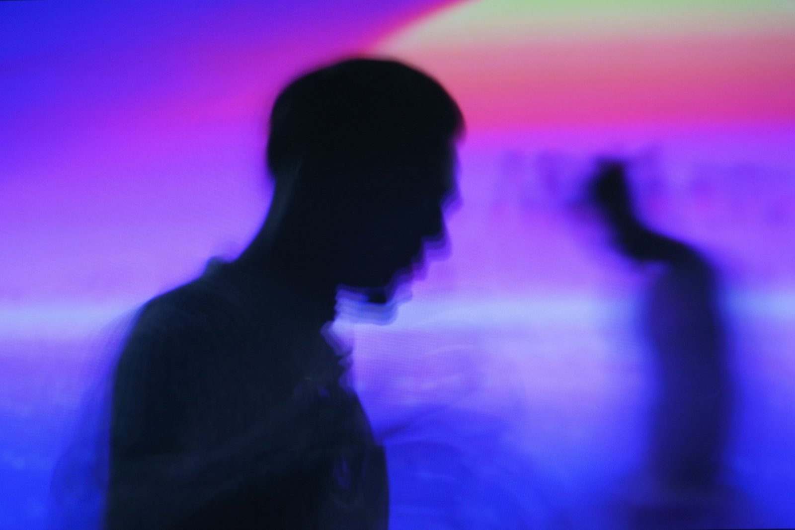 A silhouetted figure in sharp profile against a blurred, glowing crowd, individually distinct but lost in the larger scene